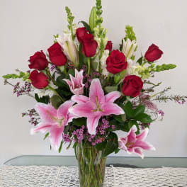 Bouquet of pink lilies and red roses in a clear glass vase