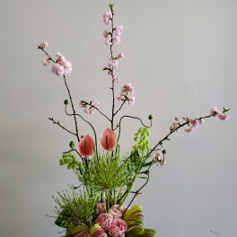 Tall floral arrangement with pink blossoms and two pink anthuriums