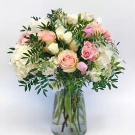 Pink and white roses arranged in a clear glass vase