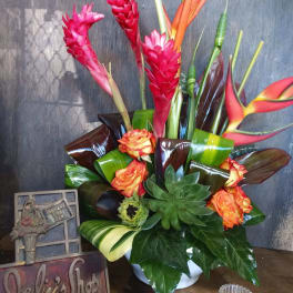 Tropical bouquet with pink ginger, orange heliconia, roses, and succulents in a white vase