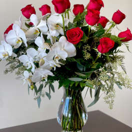 Red roses and white orchids in a clear glass vase