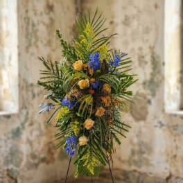 Tall floral standing spray with peach roses, blue flowers, and tropical greenery