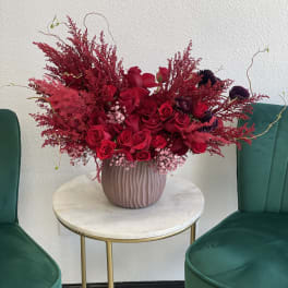 Red rose arrangement in a ribbed pink vase on a small round table