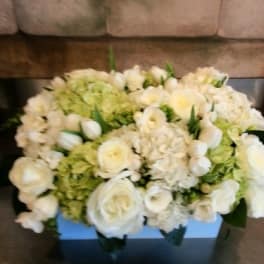 White floral arrangement in a square box with pale green blooms