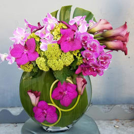 Pink orchids and calla lilies arranged in a glass vase