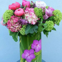 Pink and lavender flowers arranged in a tall glass vase