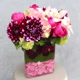 Pink and purple floral arrangement in a clear rectangular vase