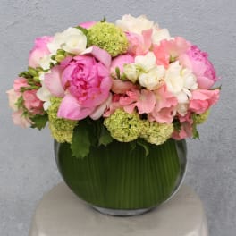 Pink and white flowers arranged in a round glass vase