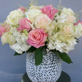 Pink and white roses arranged in a patterned white vase
