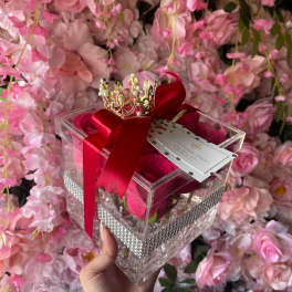 Clear gift box with pink roses, red ribbon, and a small crown