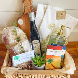 Gift basket with olive oil, towels, soap, chocolate, and a small succulent