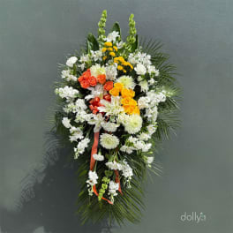 Standing floral spray with white, yellow, and orange flowers on a palm backdrop