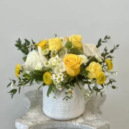 Yellow and white roses arranged in a white vase