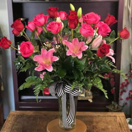 Pink and red roses with pink lilies in a glass vase