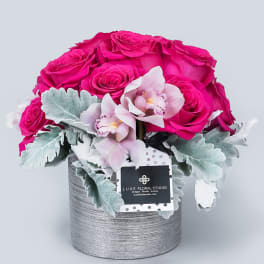 Pink roses and pale orchids in a silver round box