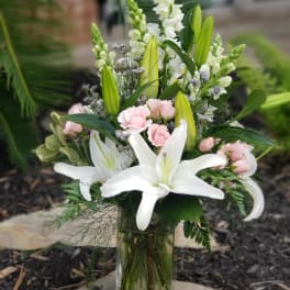 White lilies and pink roses arranged in a glass vase