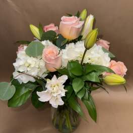 Pink roses and white hydrangeas in a glass vase with lily buds