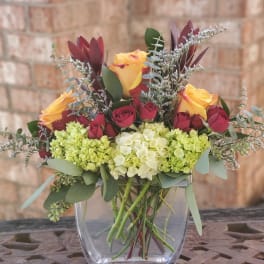 Bouquet of yellow and red roses in a clear glass vase