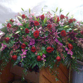 Large casket spray with red roses, lilies, and pink filler flowers