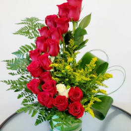 Red roses arranged in a clear glass vase with yellow filler flowers