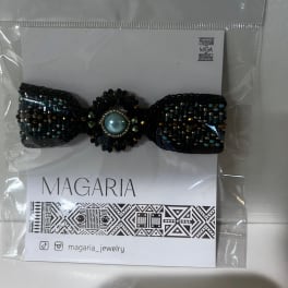 Beaded black bow hair accessory in plastic packaging