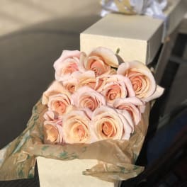 Bouquet of pale peach roses wrapped in brown paper