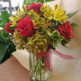 Bouquet of red roses and yellow alstroemeria in a glass vase