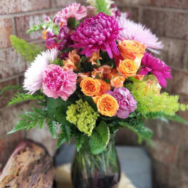 Mixed bouquet of pink, purple, and orange flowers in a glass vase