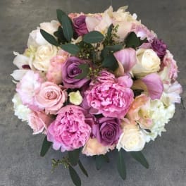 Round bouquet of pink, purple, and white flowers with dark foliage