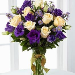 Bouquet of cream and purple roses in a clear glass vase