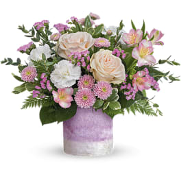 Pink and white mixed flower arrangement in a lavender vase