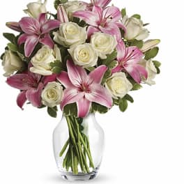 Pink lilies and white roses arranged in a clear glass vase