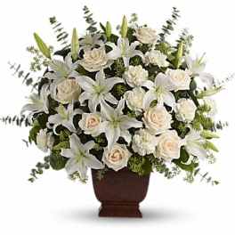 White lilies and cream roses arranged in a brown urn vase