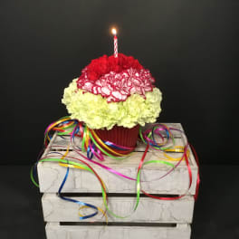 Carnation cupcake arrangement with a lit candle and colorful ribbons