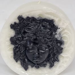 Round white candle with a black sculpted face design