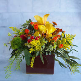 Yellow lilies and orange roses in a burgundy vase