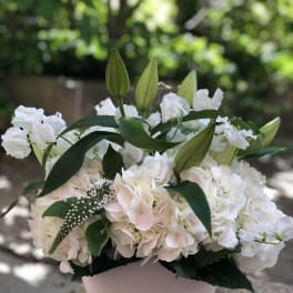 White floral arrangement with lilies and hydrangeas in a pale vase