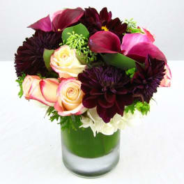 Bouquet of dark purple flowers and pink roses in a glass vase