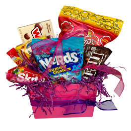Pink gift box filled with assorted candy bags and boxes with purple paper shred and ribbons
