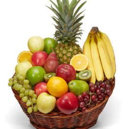 Basket of assorted fruit including bananas, pineapple, grapes, apples, and citrus