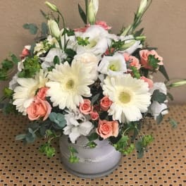 Bouquet of white gerbera daisies and peach roses in a gray vase