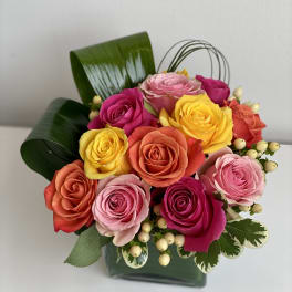 Colorful rose bouquet in a dark green box with decorative leaves