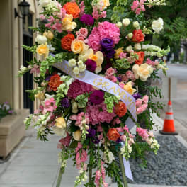 Large standing floral spray with pink, orange, yellow, and white blooms on an easel.