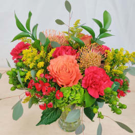 Mixed bouquet in a clear glass vase with coral roses and pink carnations