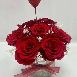 Red roses in a silver vase with a glitter heart pick