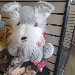 Gray and white plush dog toy with a red scarf on a store shelf
