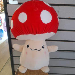 Plush mushroom toy with a red polka-dot cap and smiling face displayed on a shelf