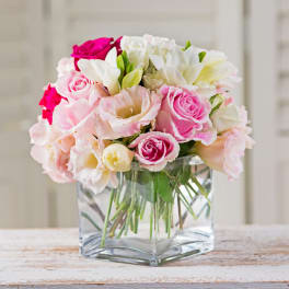 Pink and white rose bouquet in a clear square vase