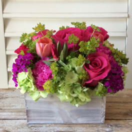 Pink roses and tulips arranged with green hydrangeas in a wooden box