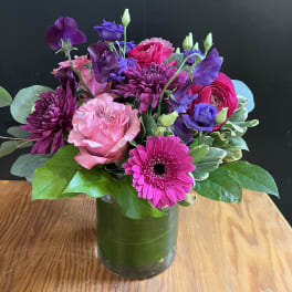 Mixed bouquet of pink, purple, and magenta flowers in a glass vase
